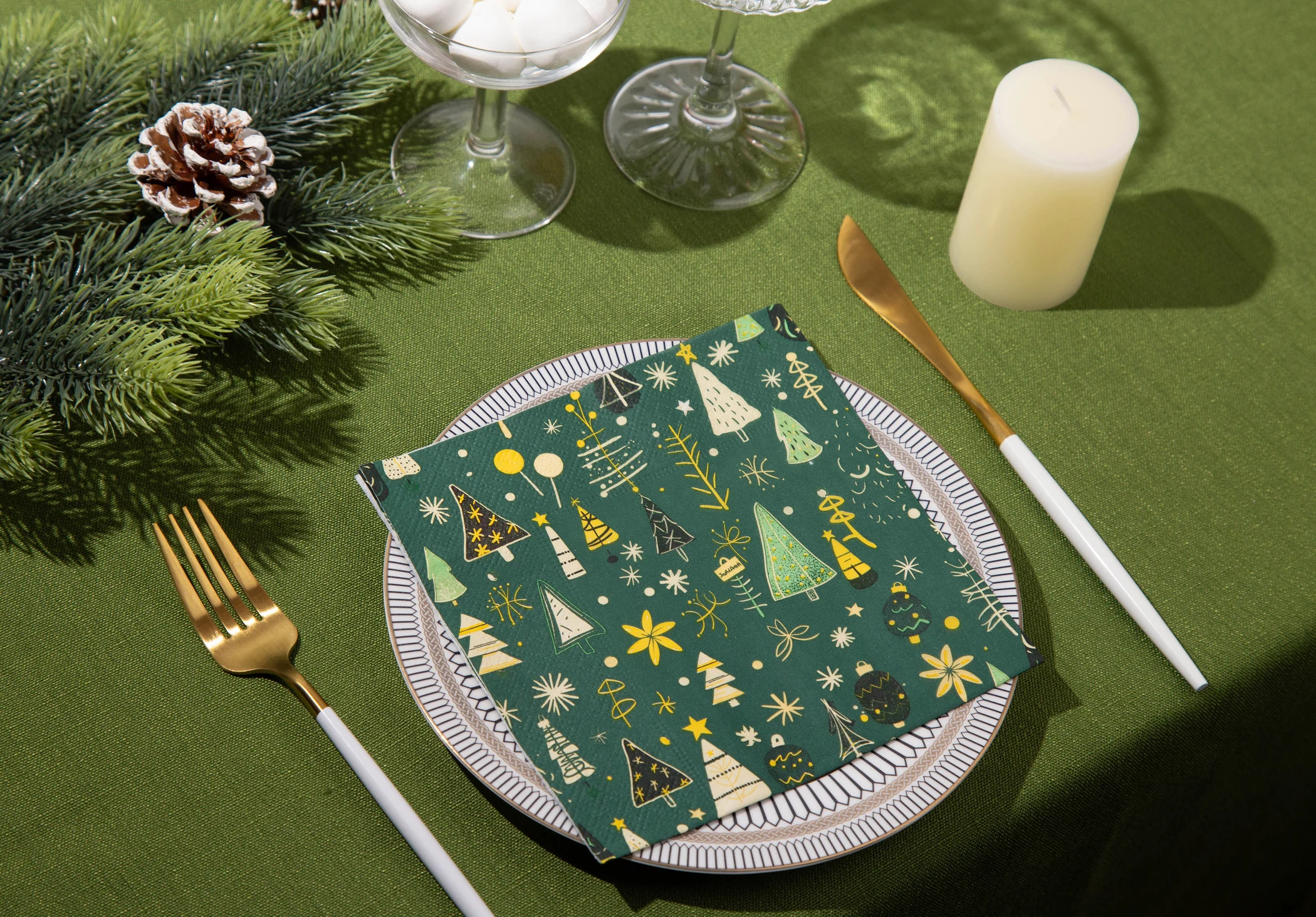 Festive Green napkins with evergreen branches, candlelight and gold cutlery